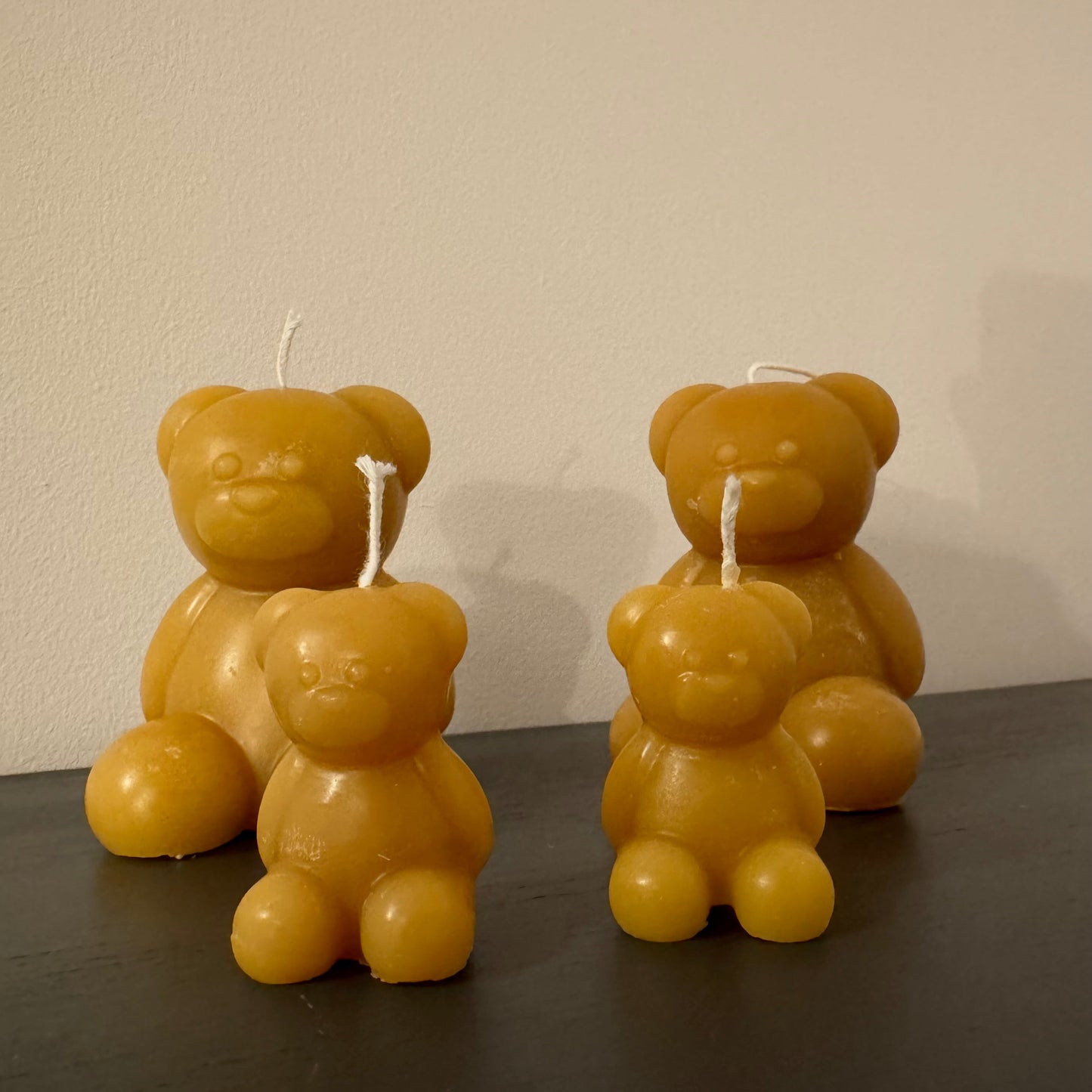 A family of four beeswax bear candles sits against a white background, they look like a family and create a natural, unique present