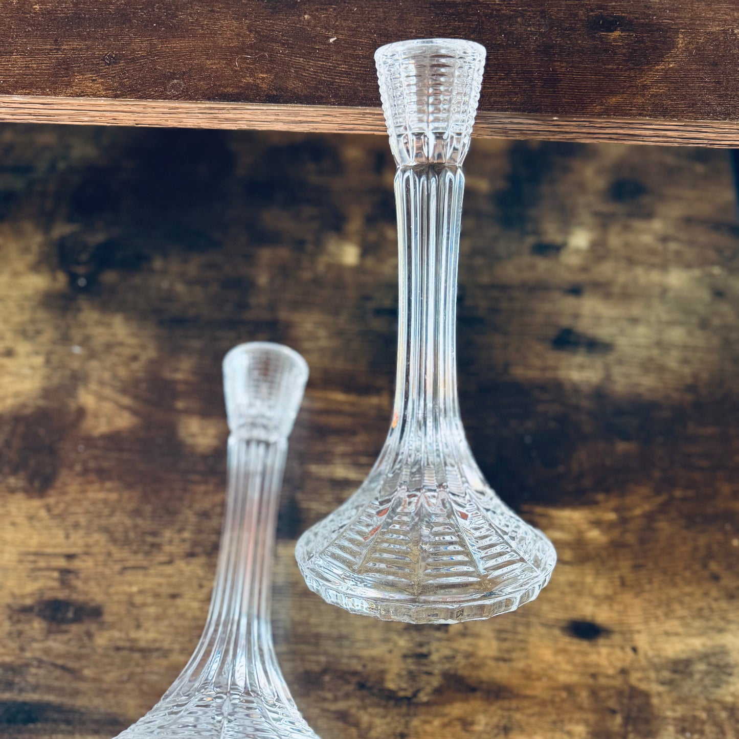 Two clear glass candle holders on a wooden surface