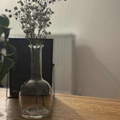 Clear glass vase with dried flowers on a wooden surface