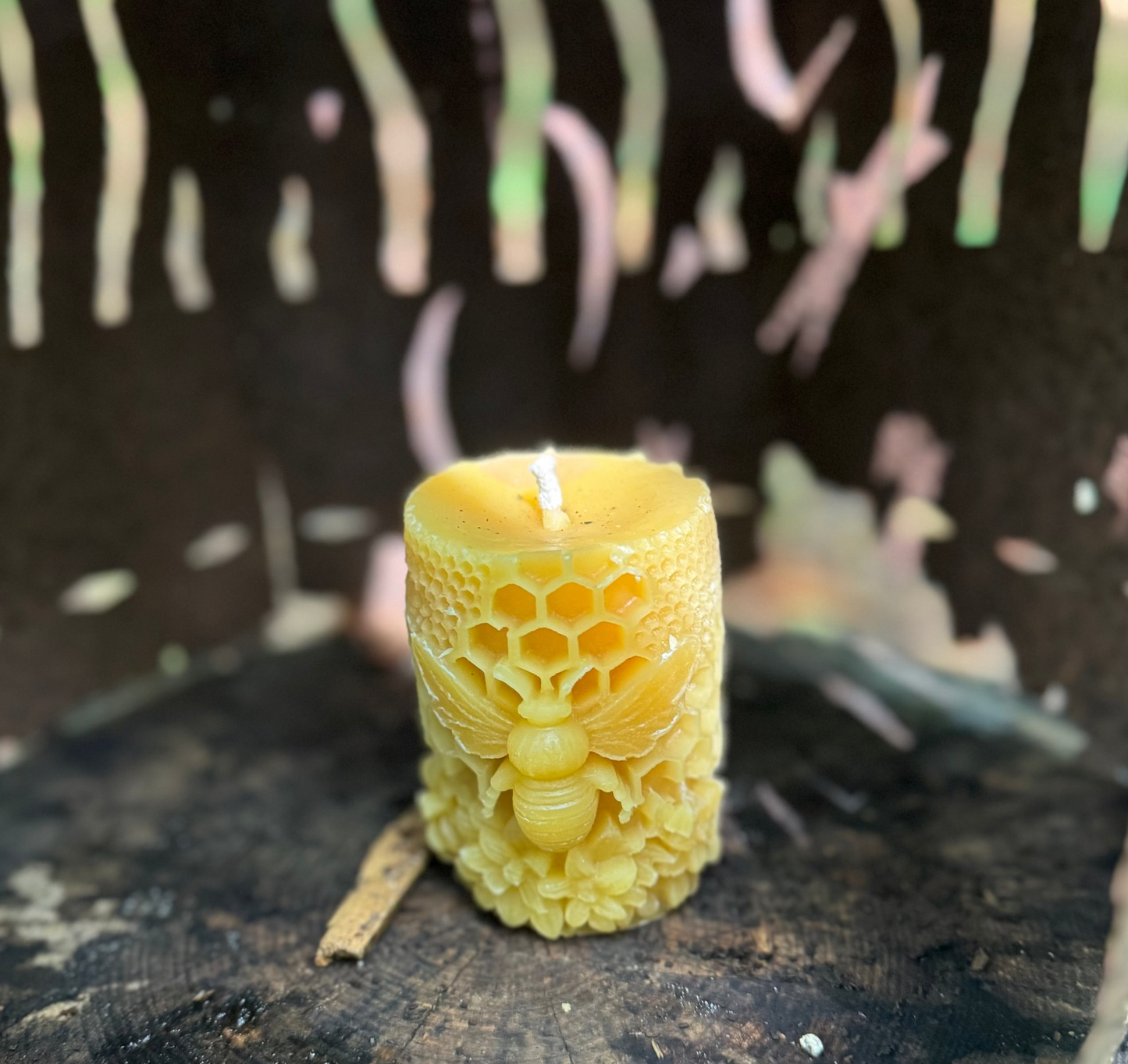 Beeswax candle with honeycomb design on a natural log and metal surface