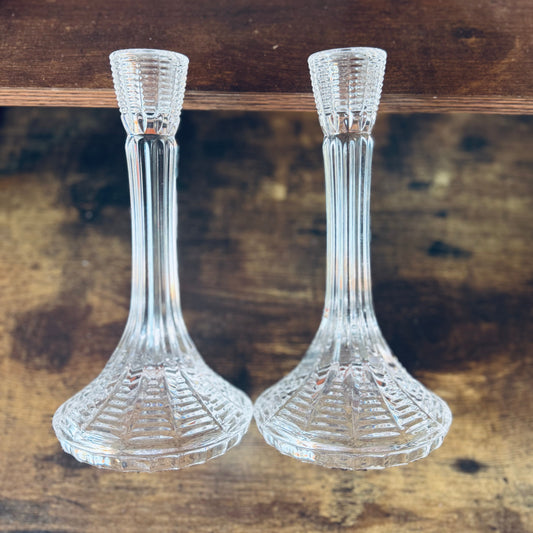 Two clear glass candle holders on a wooden surface