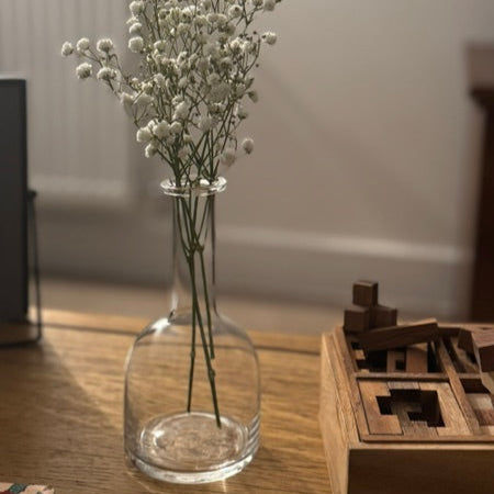Clear glass vase with dried flowers on a wooden table, blurred background