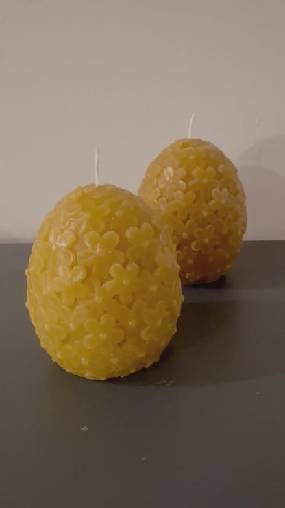 2 egg shaped domed floral candles sit in front of a white background